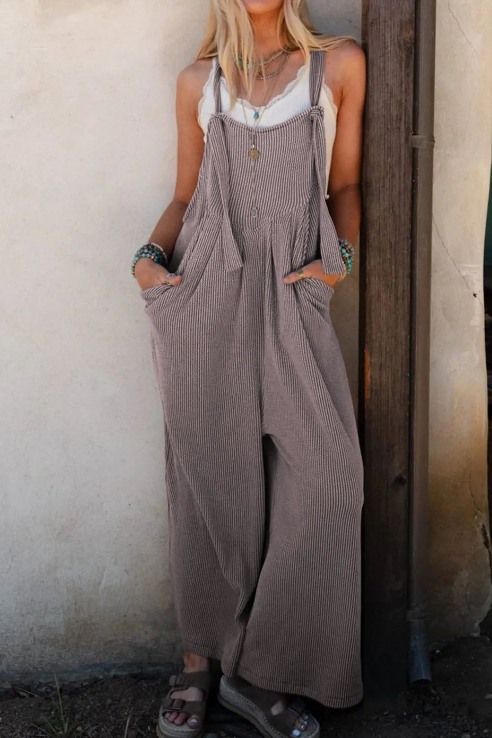 Gray wide-leg overalls with adjustable straps, deep front pocket, and center seam
