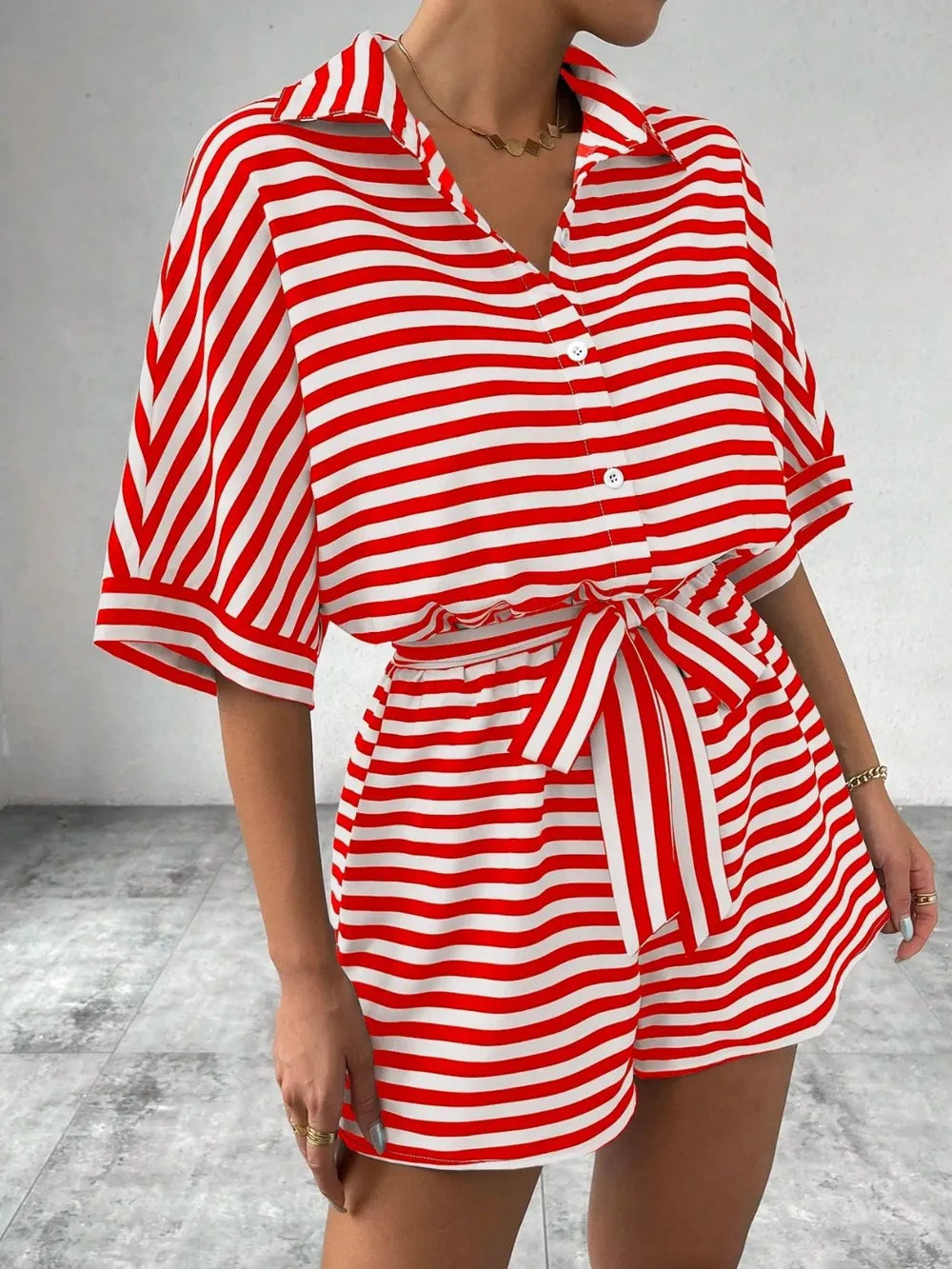 Red and white striped button-front romper with tie waist and cuffed sleeves, side view