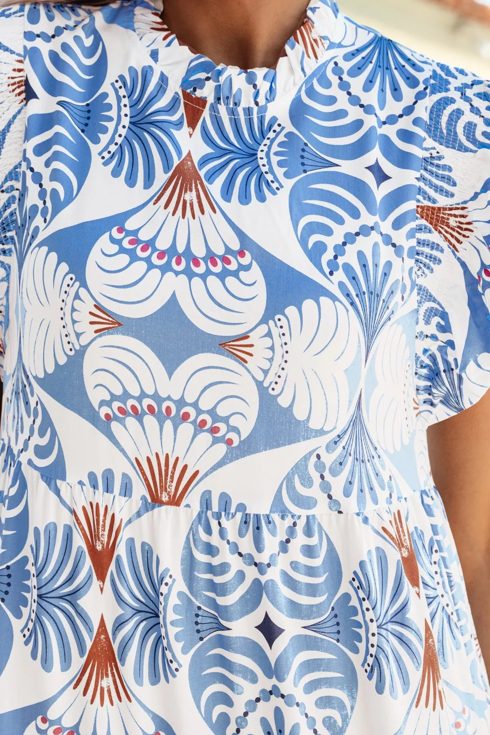 Cedar & Moore Tropical Botanic Print Flutter Sleeve Vacation Dress in blue and white with rust accents, ruffled neckline.
