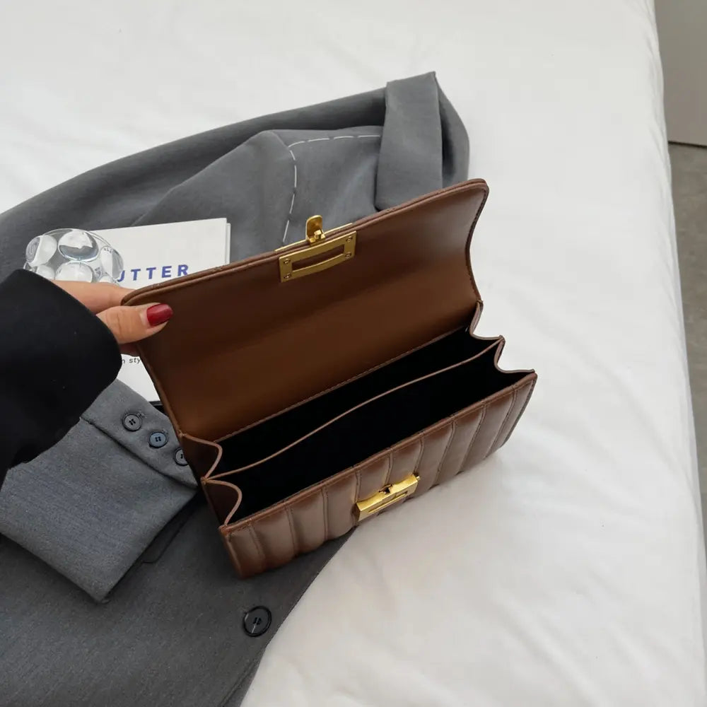 Brown crossbody bag open flap view, showing interior and gold top clasp hardware.