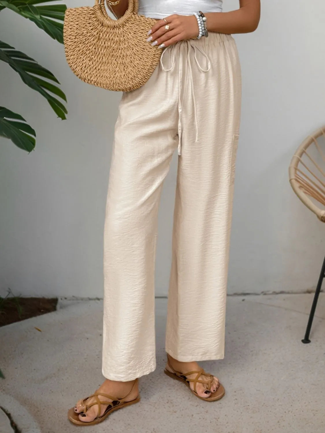 Cream drawstring wide-leg pants with elastic waistband and loose draping fit