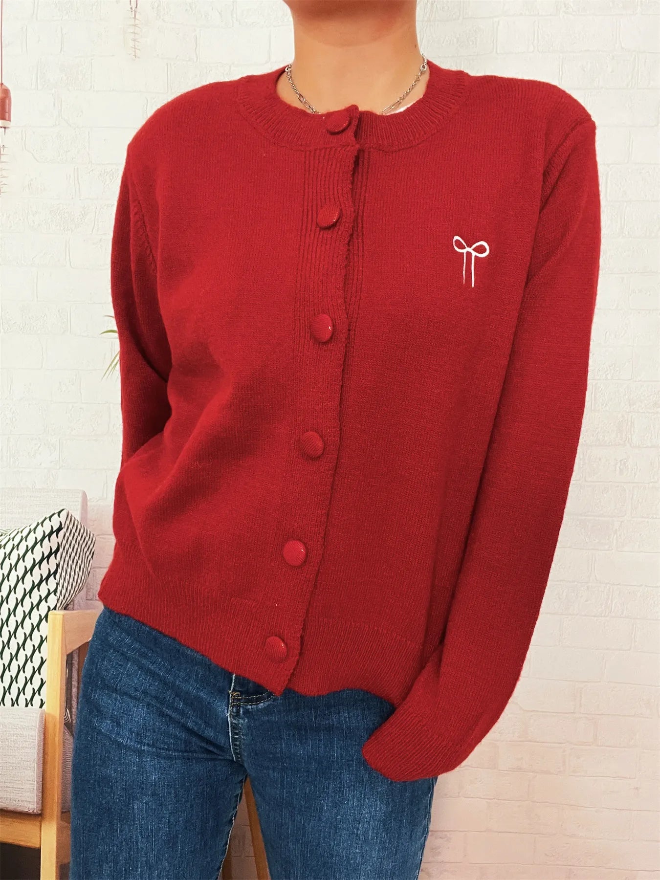 Red knit cardigan with long sleeves, button placket, and bow embroidery on chest