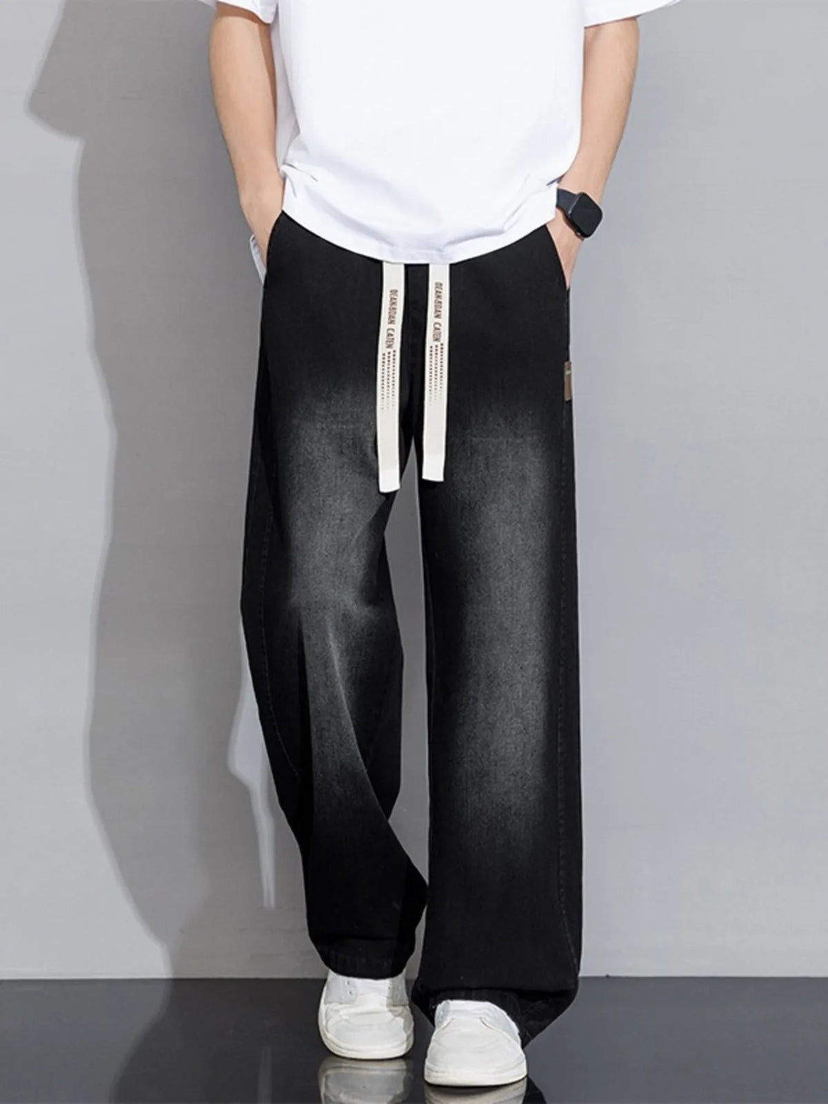 Men's black wide-leg drawstring jeans with two long tie straps at waistband
