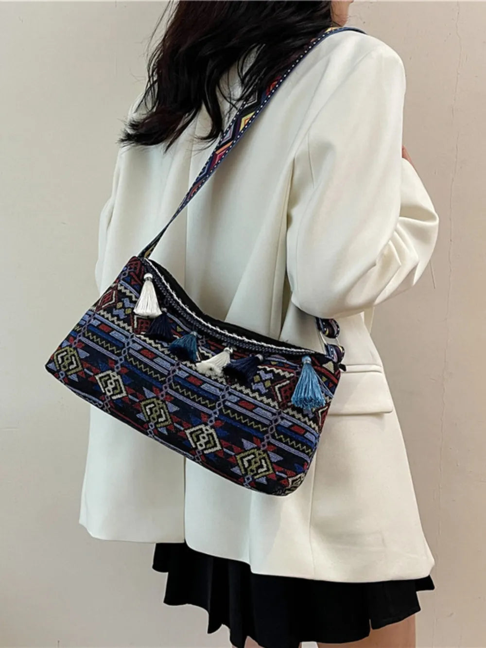 Tassel shoulder bag with adjustable strap, navy multicolor woven pattern and tassel accents.