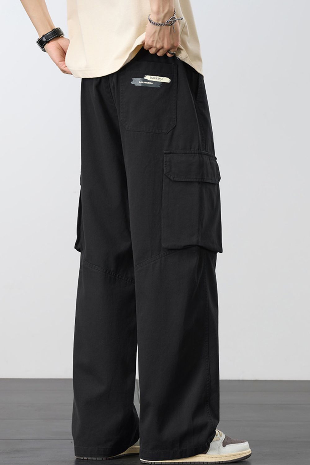 Men's loose cargo pants in black with drawstring, cargo pockets, and relaxed wide legs