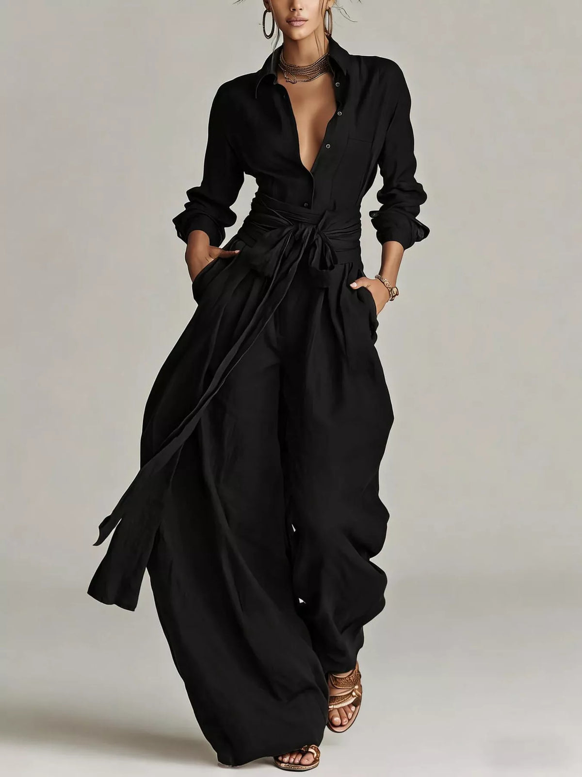 Black long-sleeve button-down waist-tie jumpsuit with open neckline and wide legs