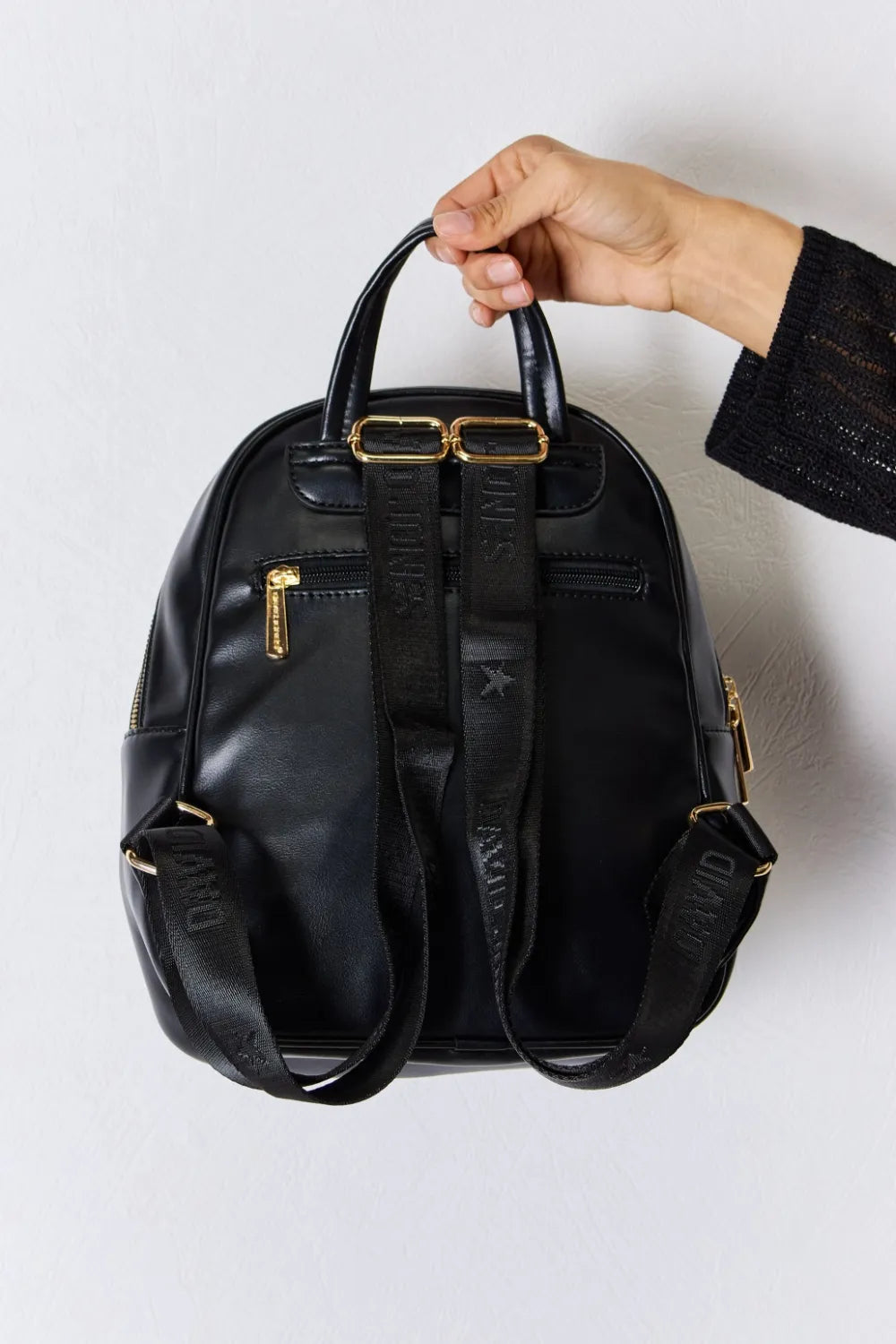 Black vegan leather mini backpack with double straps and gold-tone buckle hardware