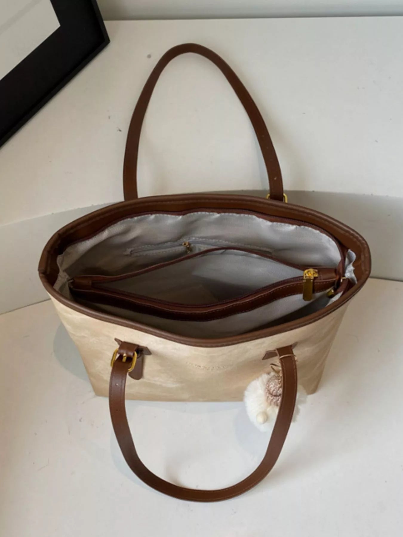 Shoulder bag in beige PU with brown handles and a plush white charm