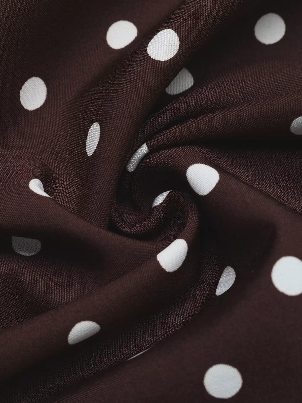 Coffee brown polka dot stretch fabric close-up with soft drape