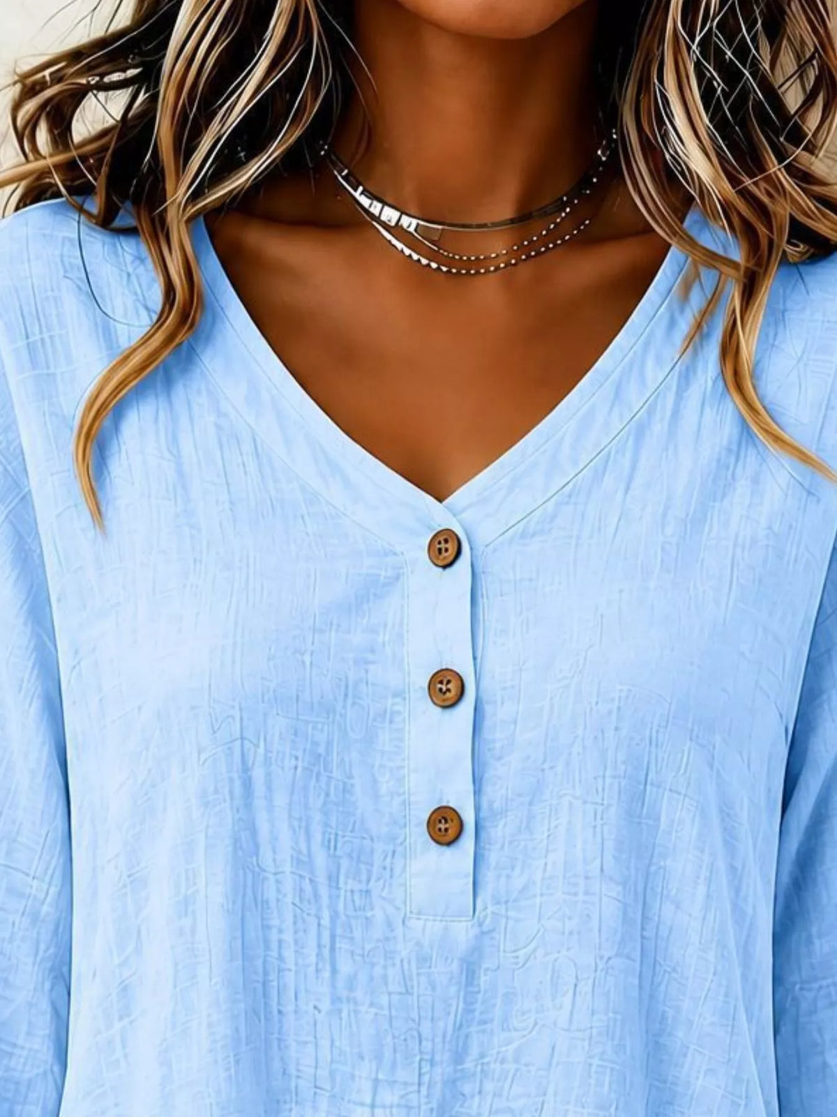 Light blue v-neck blouse detail view with 3-button front and long sleeves