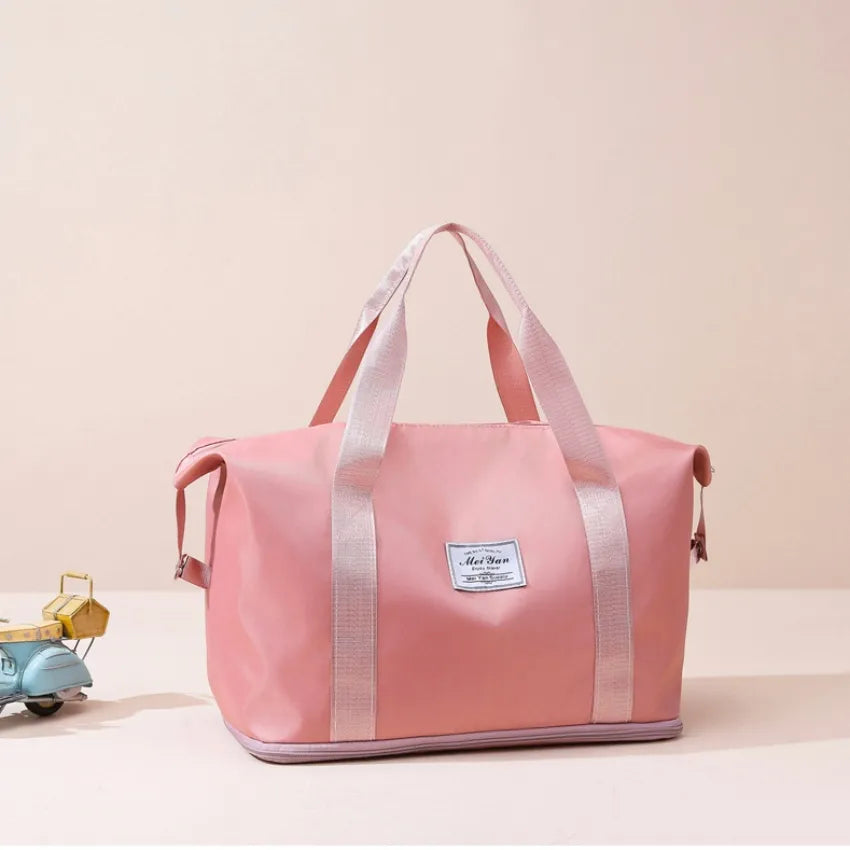 Dusty pink large duffle bag with long handles and front patch label