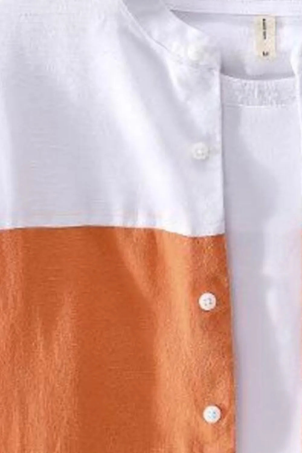Color-block button-up shirt close-up: white upper, orange lower, visible buttons