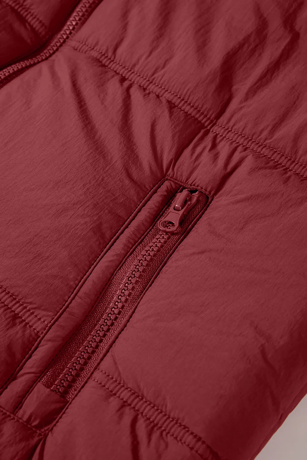 Burgundy quilted zip-up hooded vest coat close-up, stitched seams and zipper pull