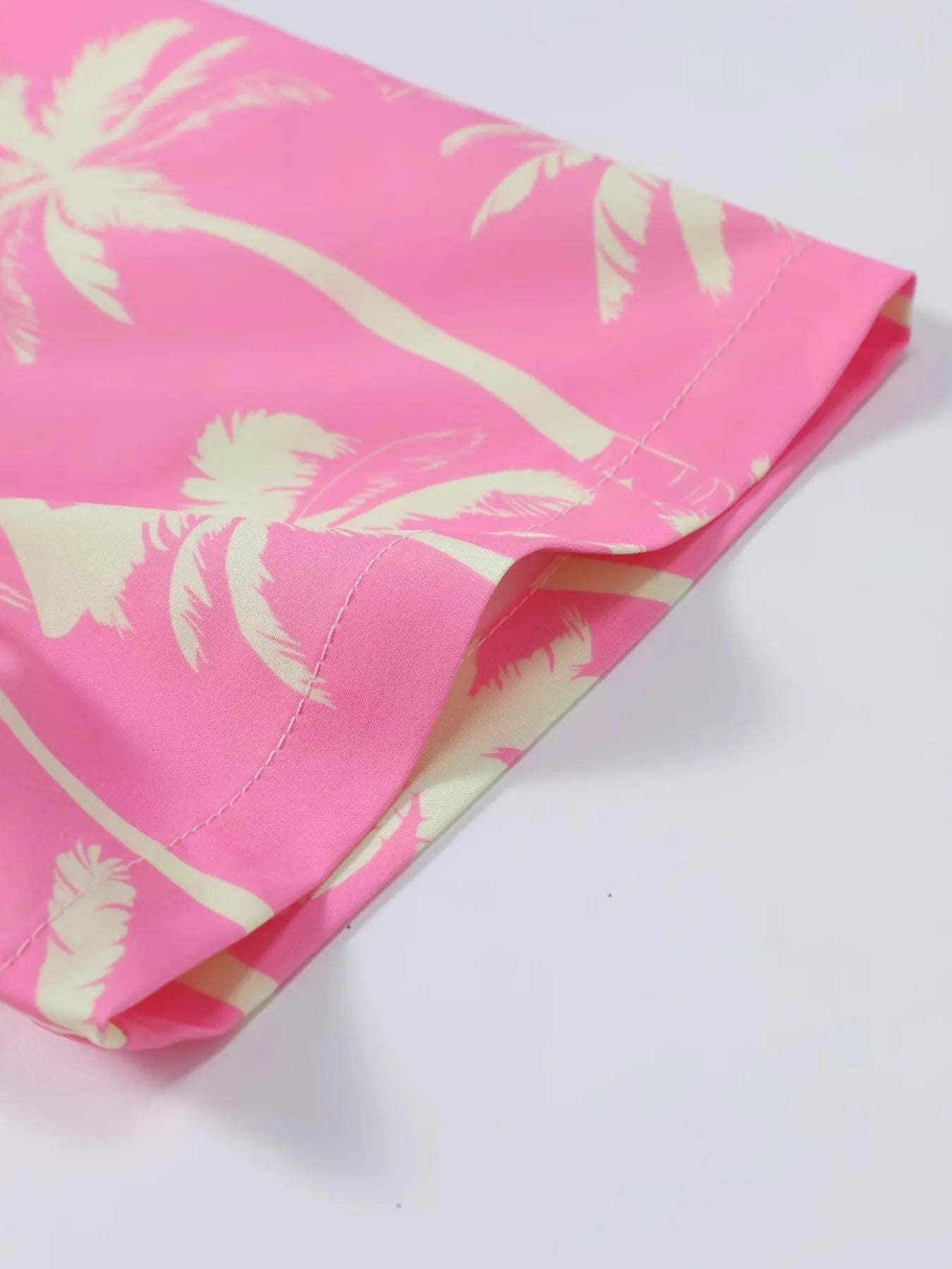 Dusty pink palm print shorts fabric close-up, side seam