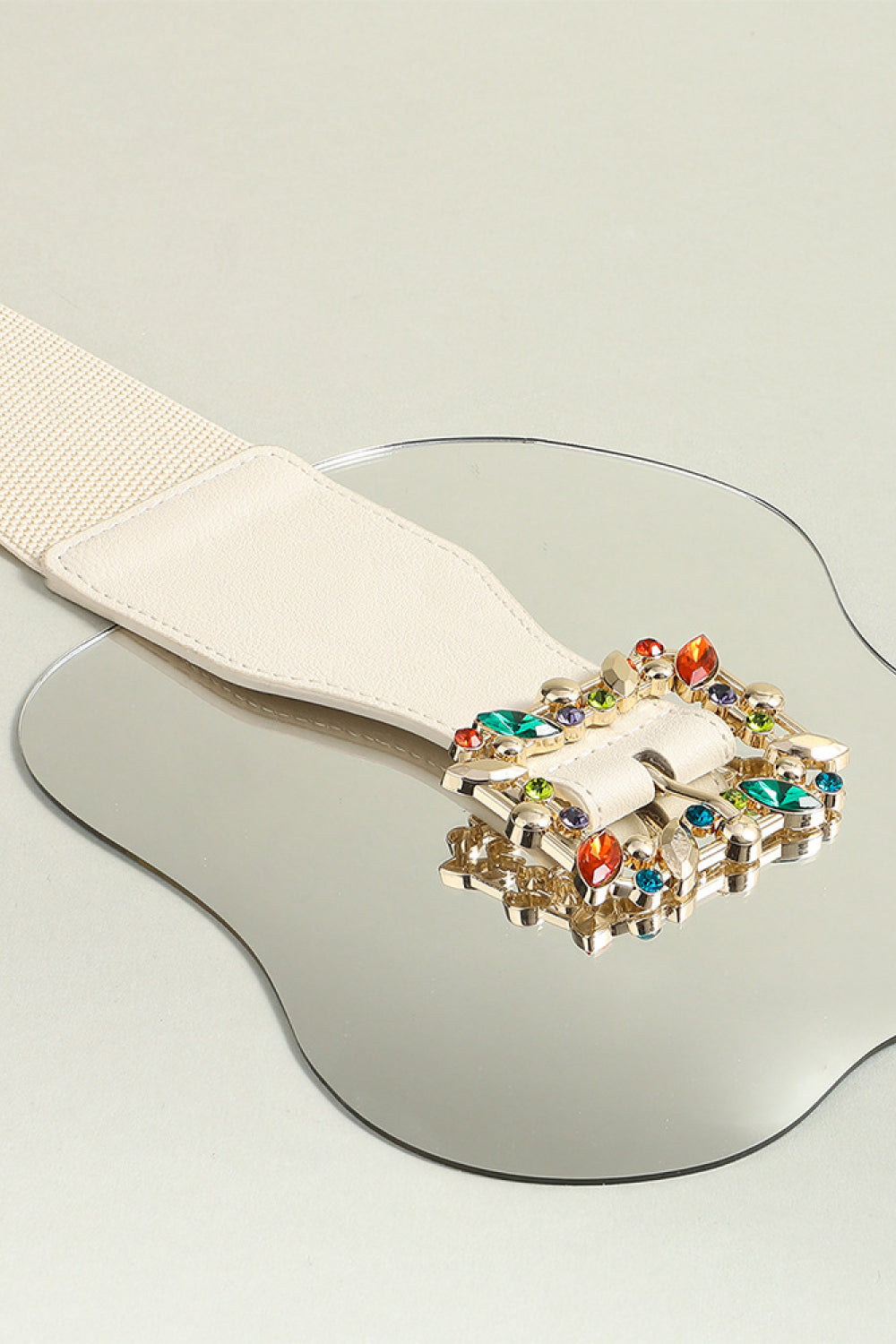 Ivory elastic belt close-up: multicolor leaf buckle with gem-like stones