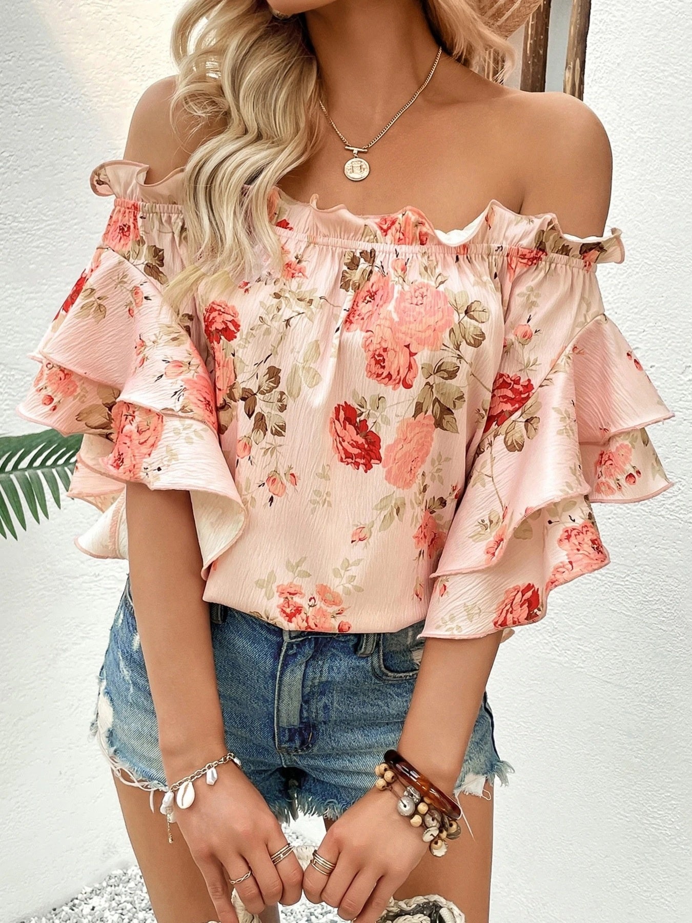 Floral print pink off-shoulder blouse with layered ruffle sleeves.