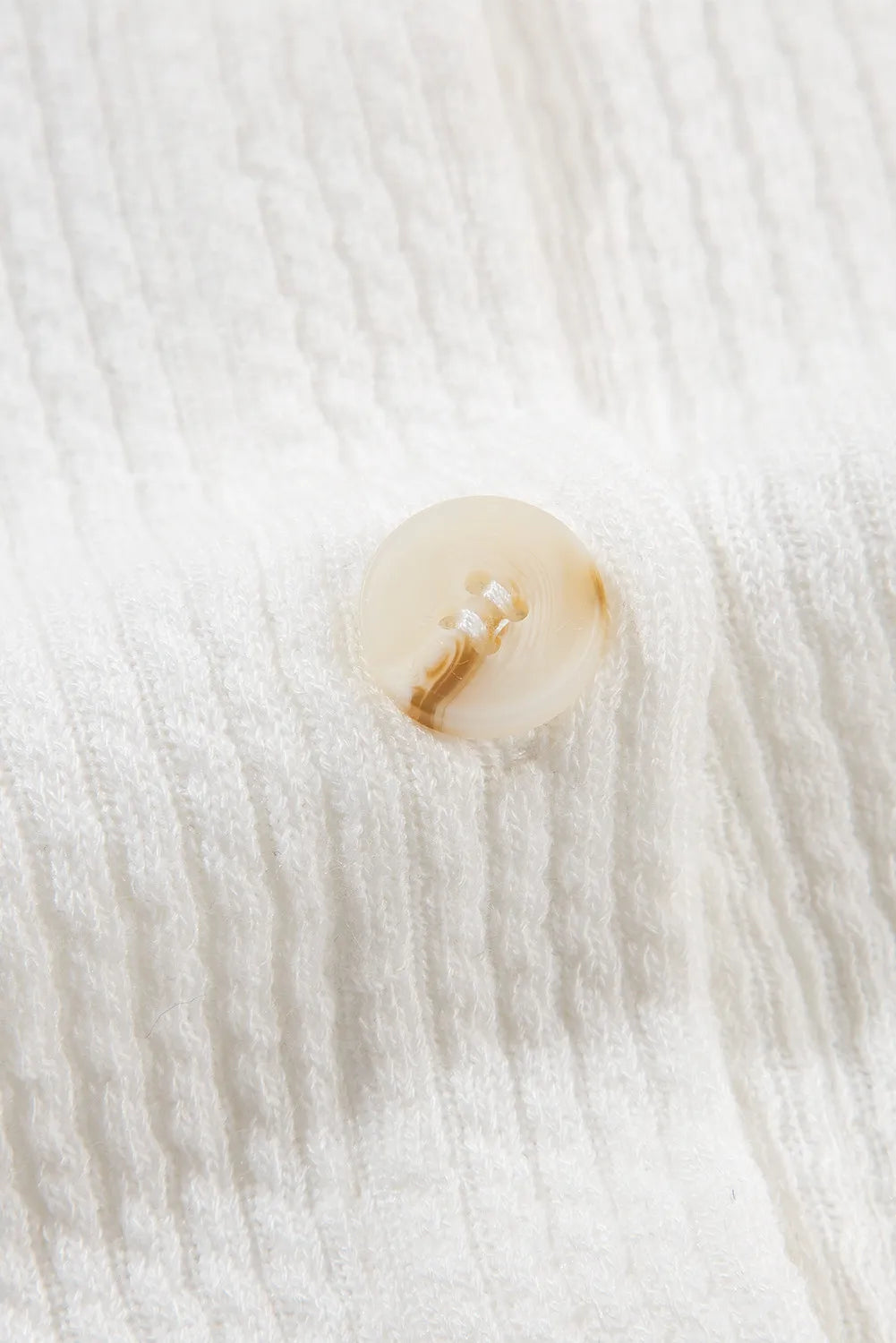 White shacket button closure detail with round light-gold button.