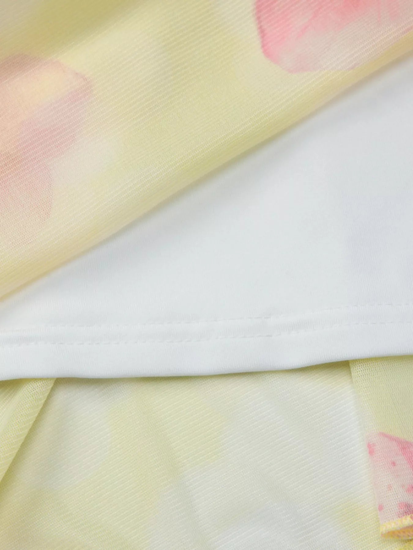 Close-up of yellow sheer fabric edge with small pink floral accents