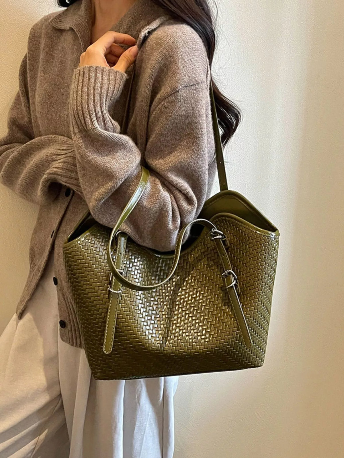 Green textured tote bag worn on shoulder, showing top handles and zip closure