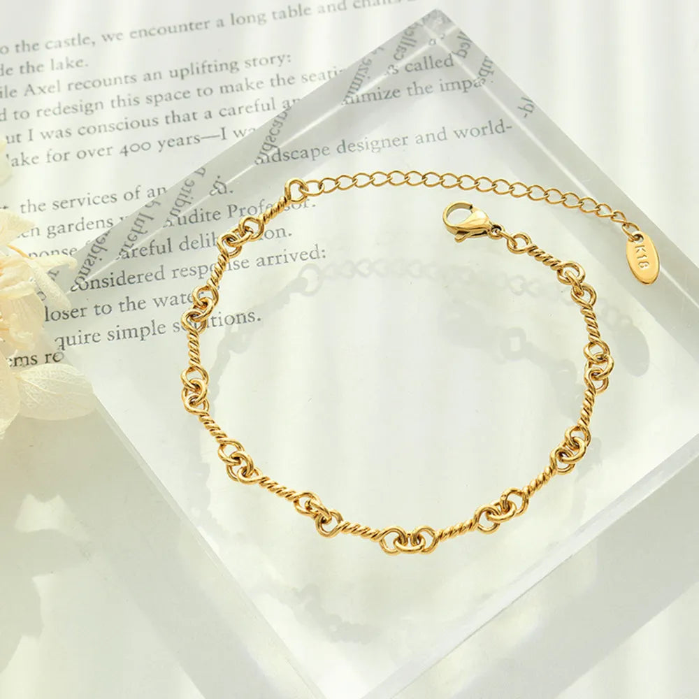 Gold link chain bracelet on jewelry card, oval tag charm near toggle clasp