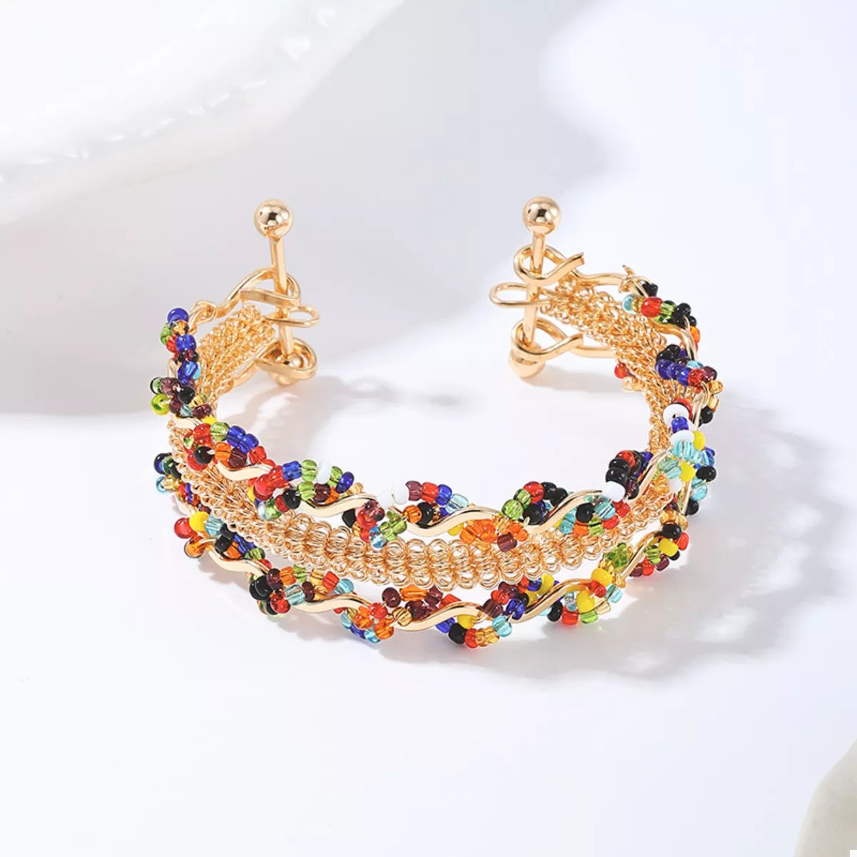 Gold open bracelet featuring three chain rows with multicolor bead fringe