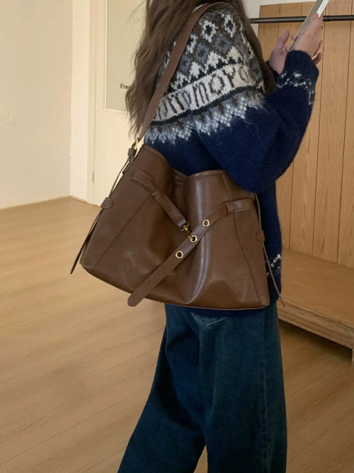 Brown buckle-detail tote bag with side pockets and shoulder strap on a model