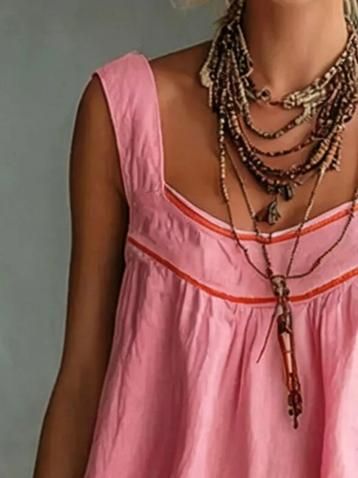 Pink sleeveless mini dress with orange trim, V neckline, and tiered ruffle skirt
