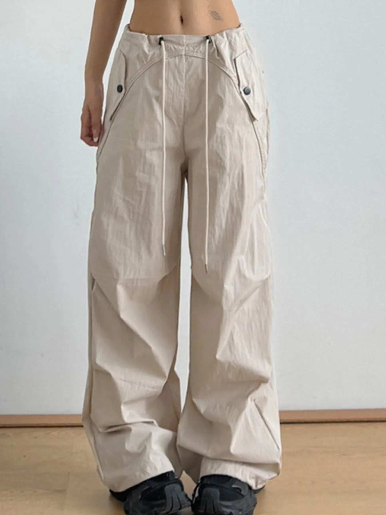 Beige relaxed wide-leg drawstring pants with front seams and flap pockets