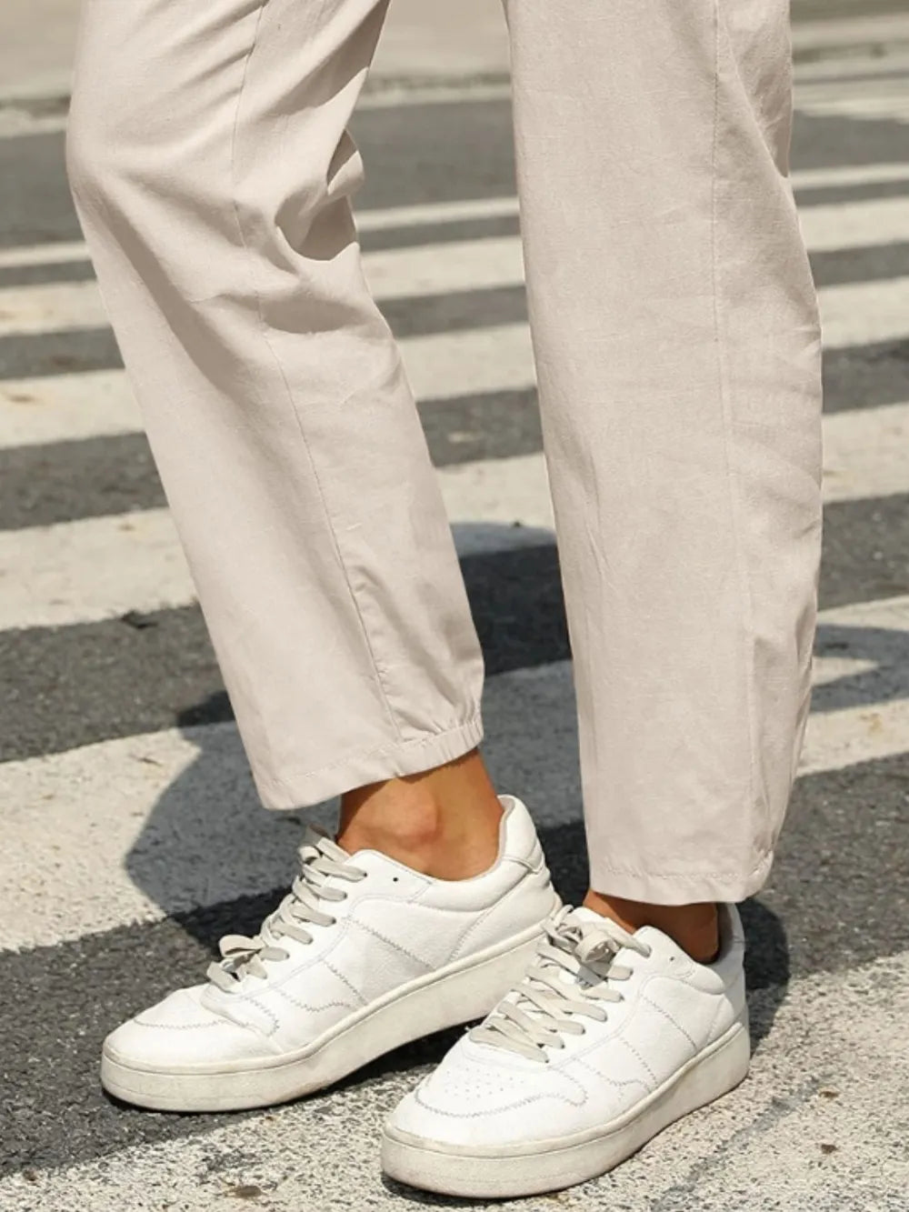 Light beige tapered ankle pants with elastic waistband and relaxed leg opening