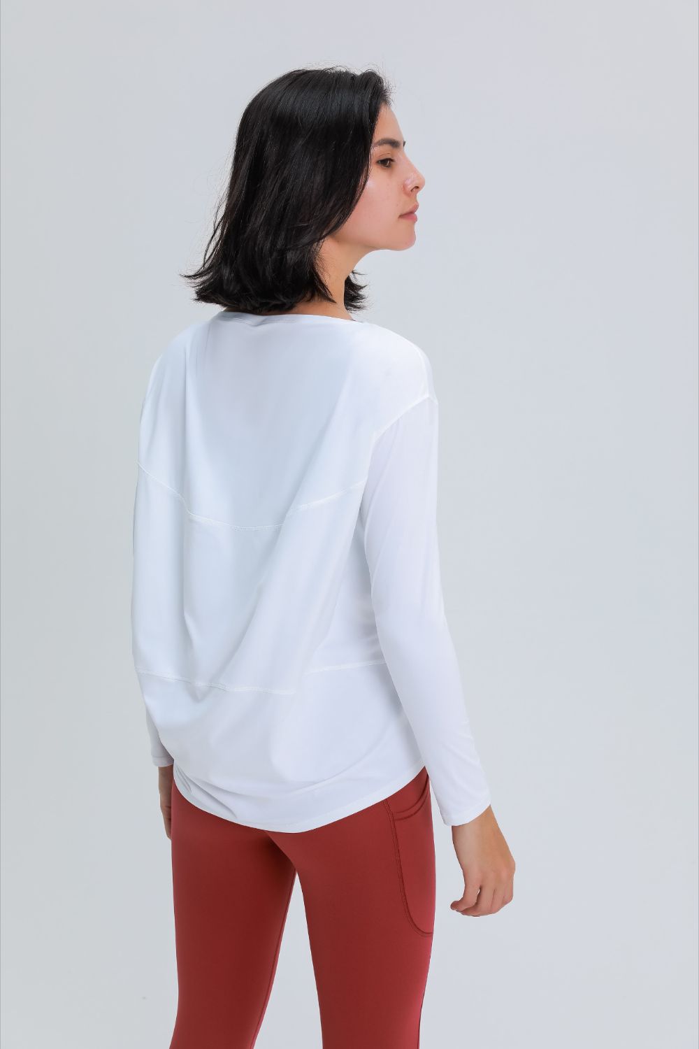 Loose fit active top in white, back view with long sleeves and loose fit silhouette.
