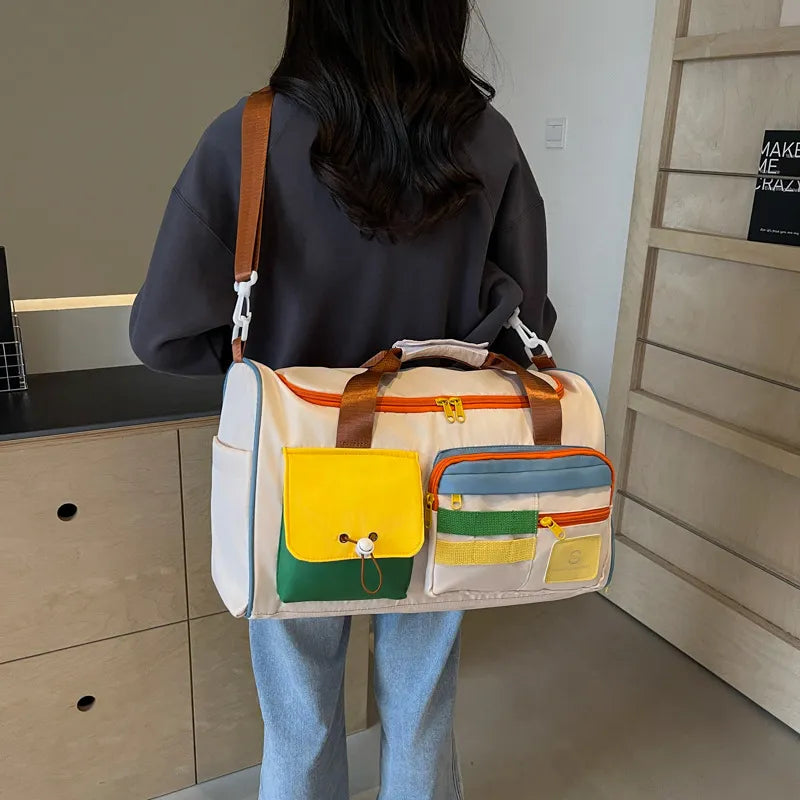 Beige duffle bag with orange trim, brown shoulder strap, and front multi-pocket layout