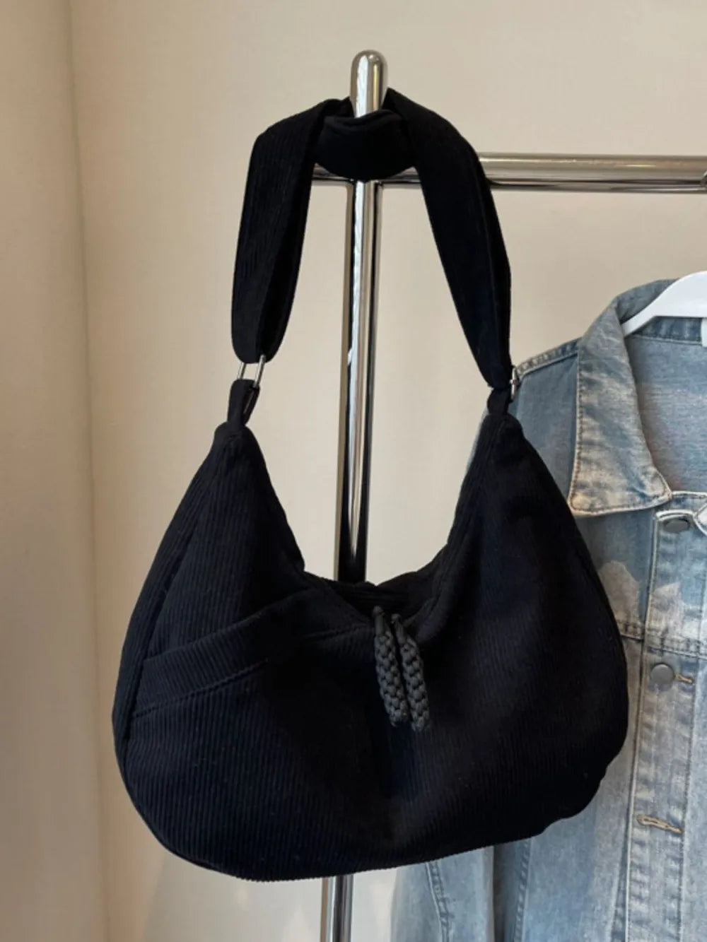 Black ribbed shoulder bag with adjustable strap and drawstring top