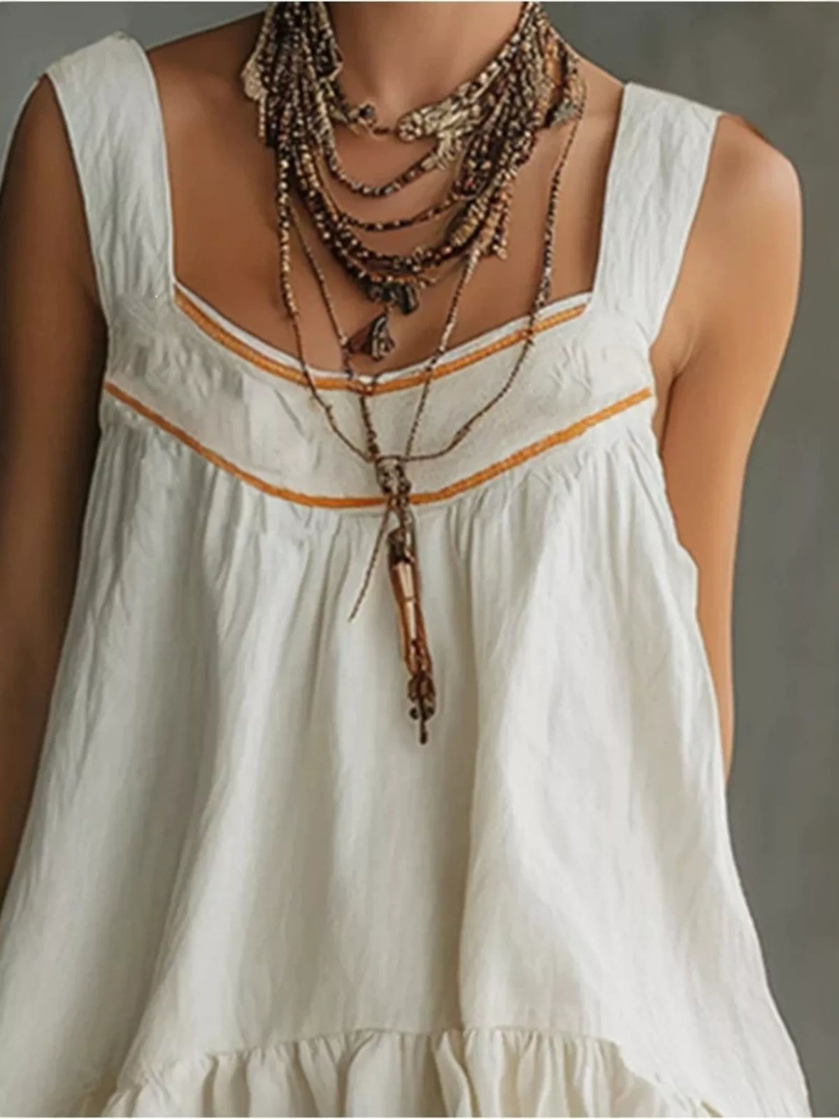 White sleeveless mini dress with orange trim, scoop neckline, and tiered ruffle layers