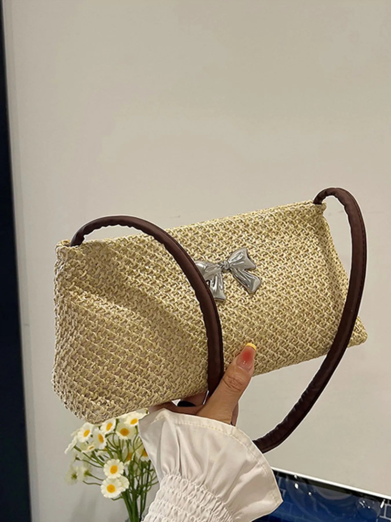 Woven straw shoulder bag with silver bow detail and brown handle, tan textured weave