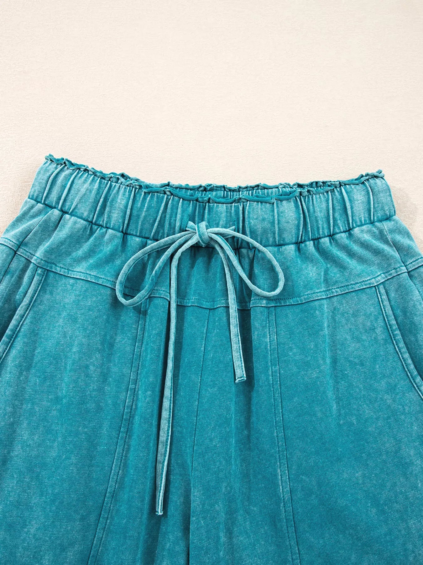Teal high-waist pants with elastic waistband and adjustable drawstring ties