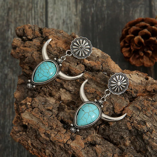 Turquoise teardrop dangle earrings with crescent horn charms and sunburst caps, silver-tone