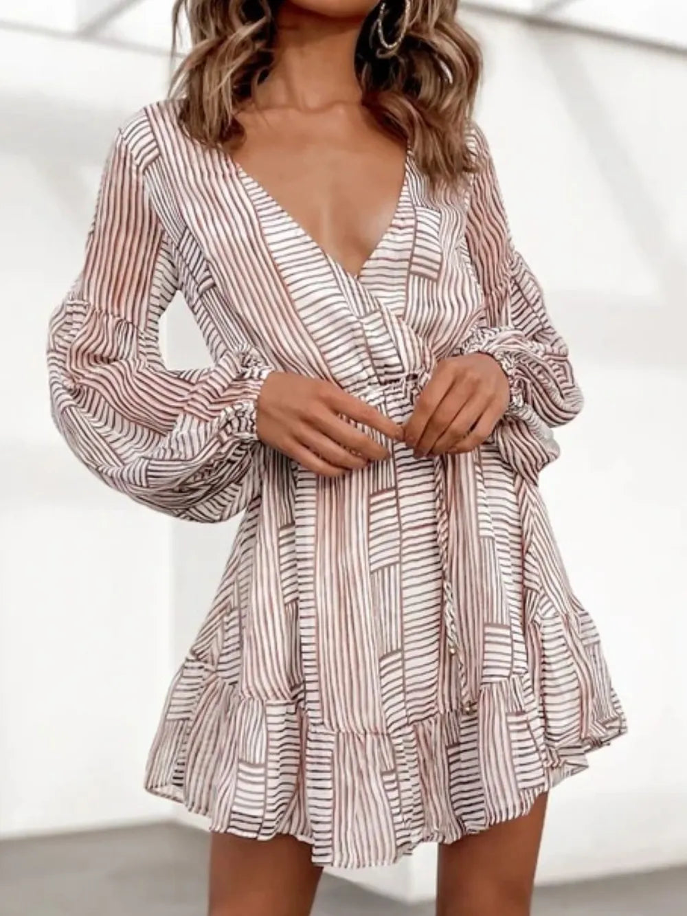 Camel-and-white striped surplice dress with V-neck, long sleeves, and cinched waist