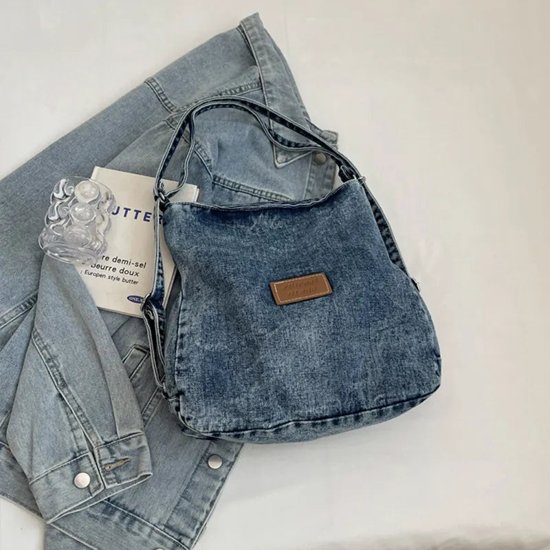 Denim shoulder bag with adjustable strap, dark blue fabric and brown front logo patch