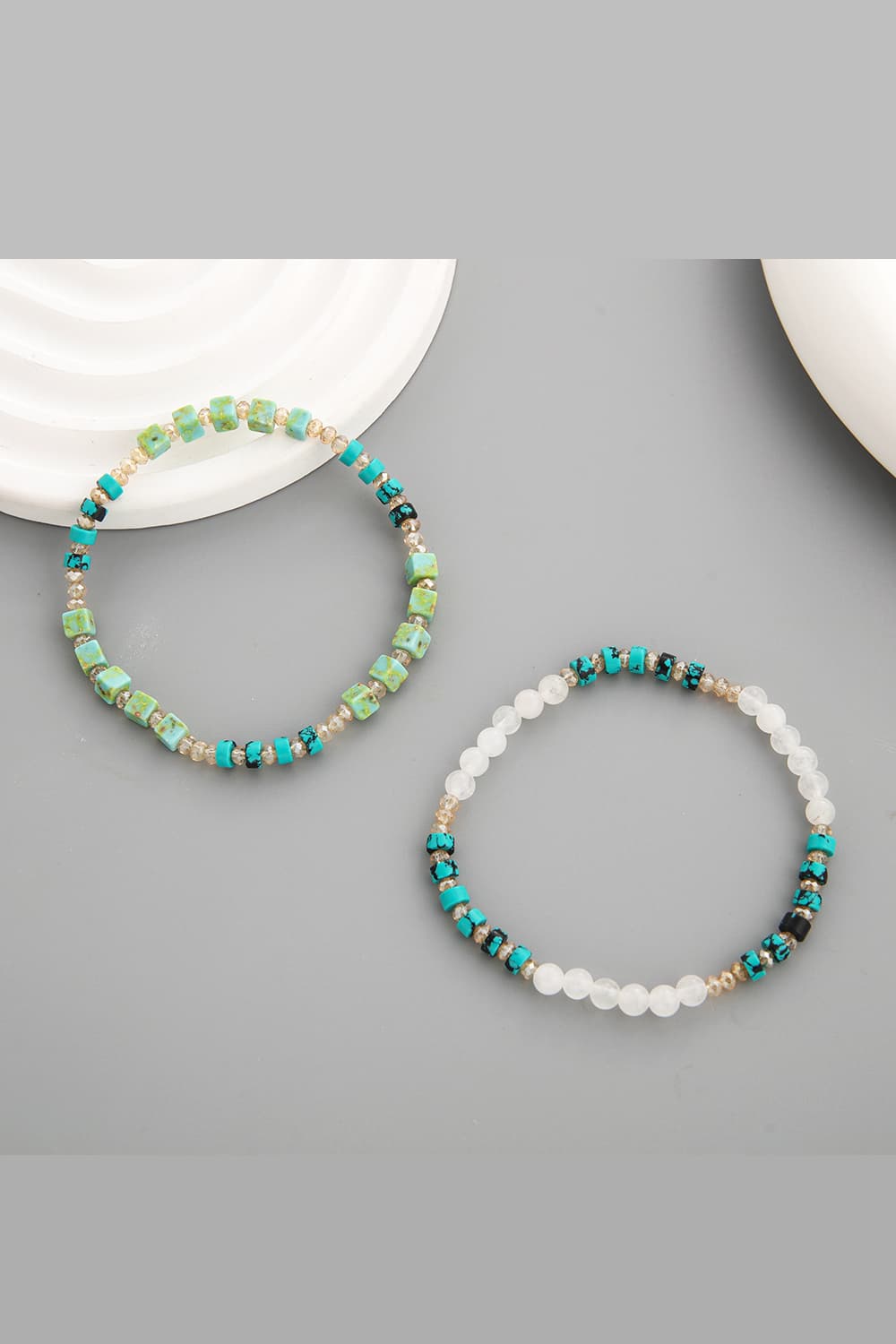 Two crystal and natural stone bracelets: teal and white beaded with gold accents