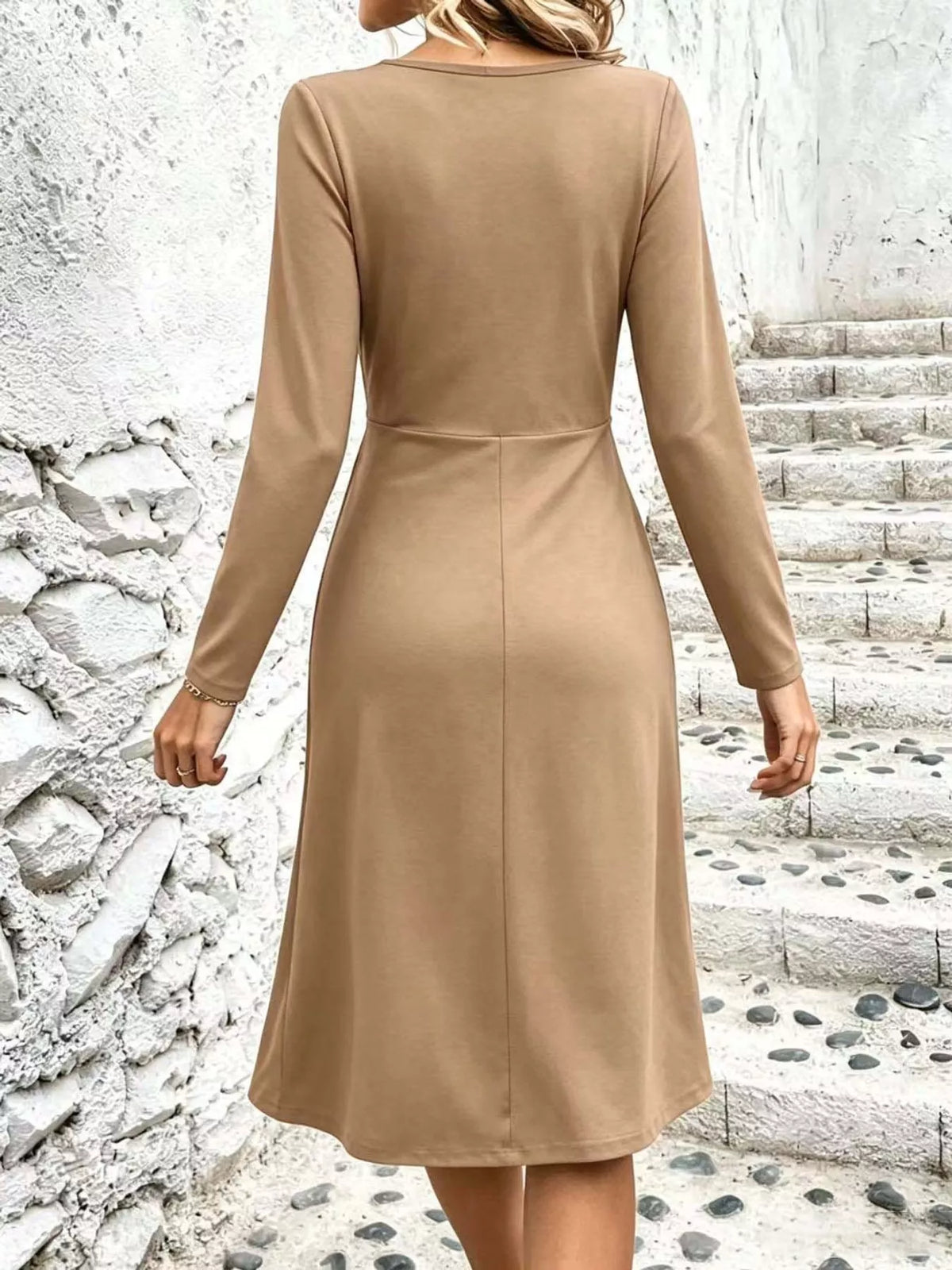 Back view of beige ruched midi dress with long sleeves and centered waist seam.