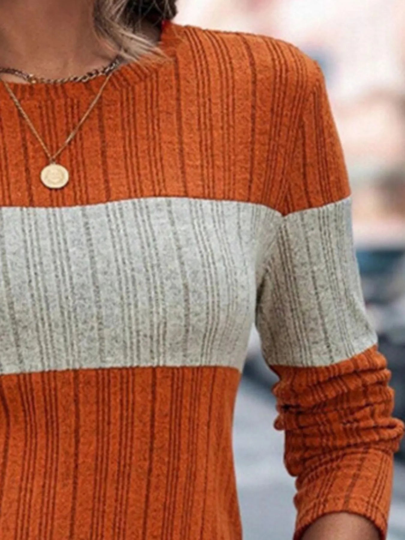 Color-block round-neck long-sleeve sweater with orange ribbed body and cream stripe.