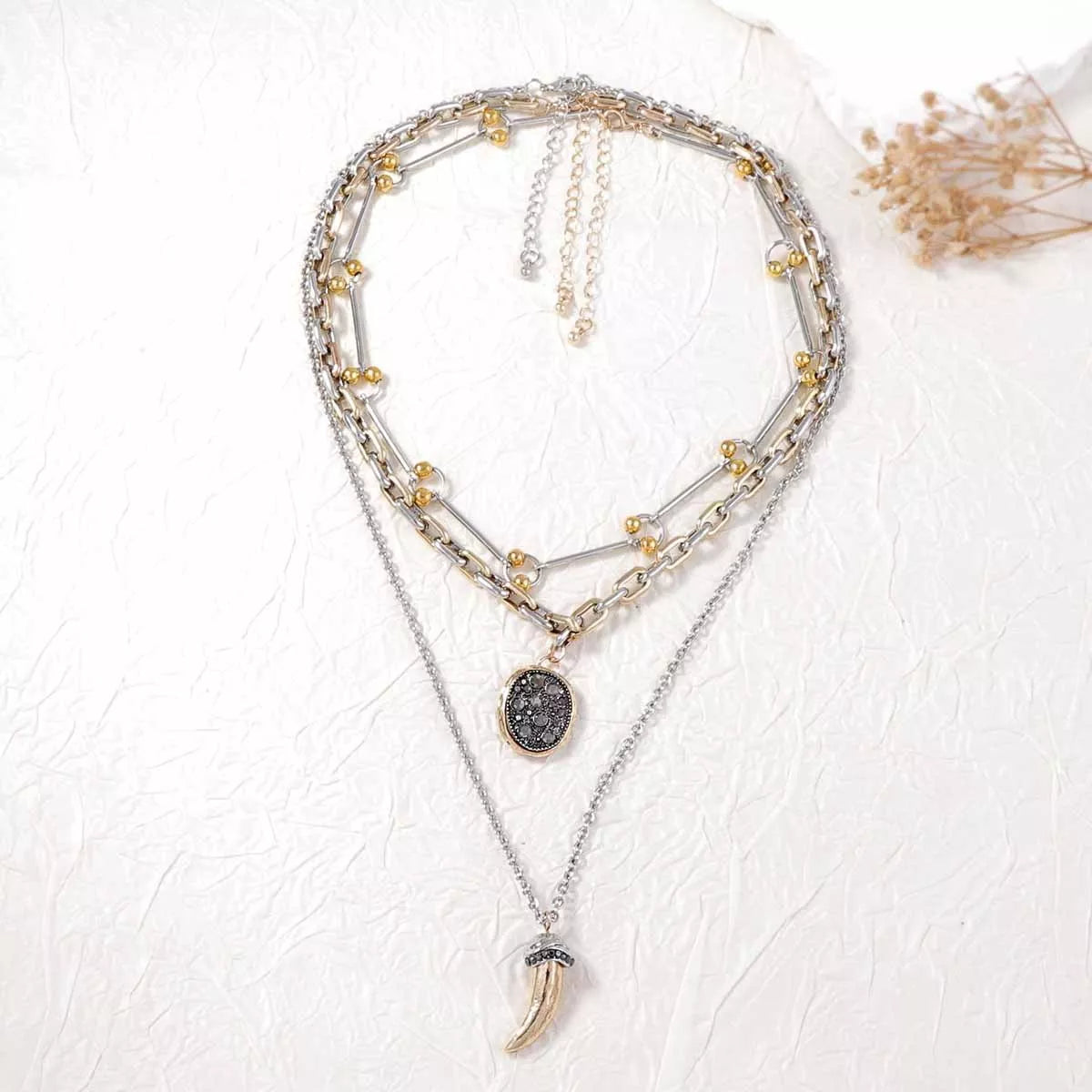 Layered gold plated chain necklace with dark round pendant and curved horn charm