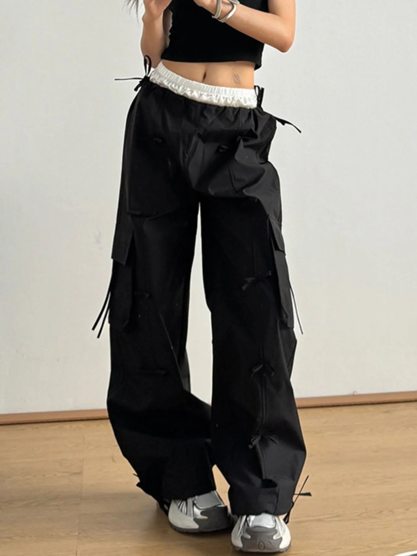 Black cargo pants with elastic waist and large cargo pockets with tie straps