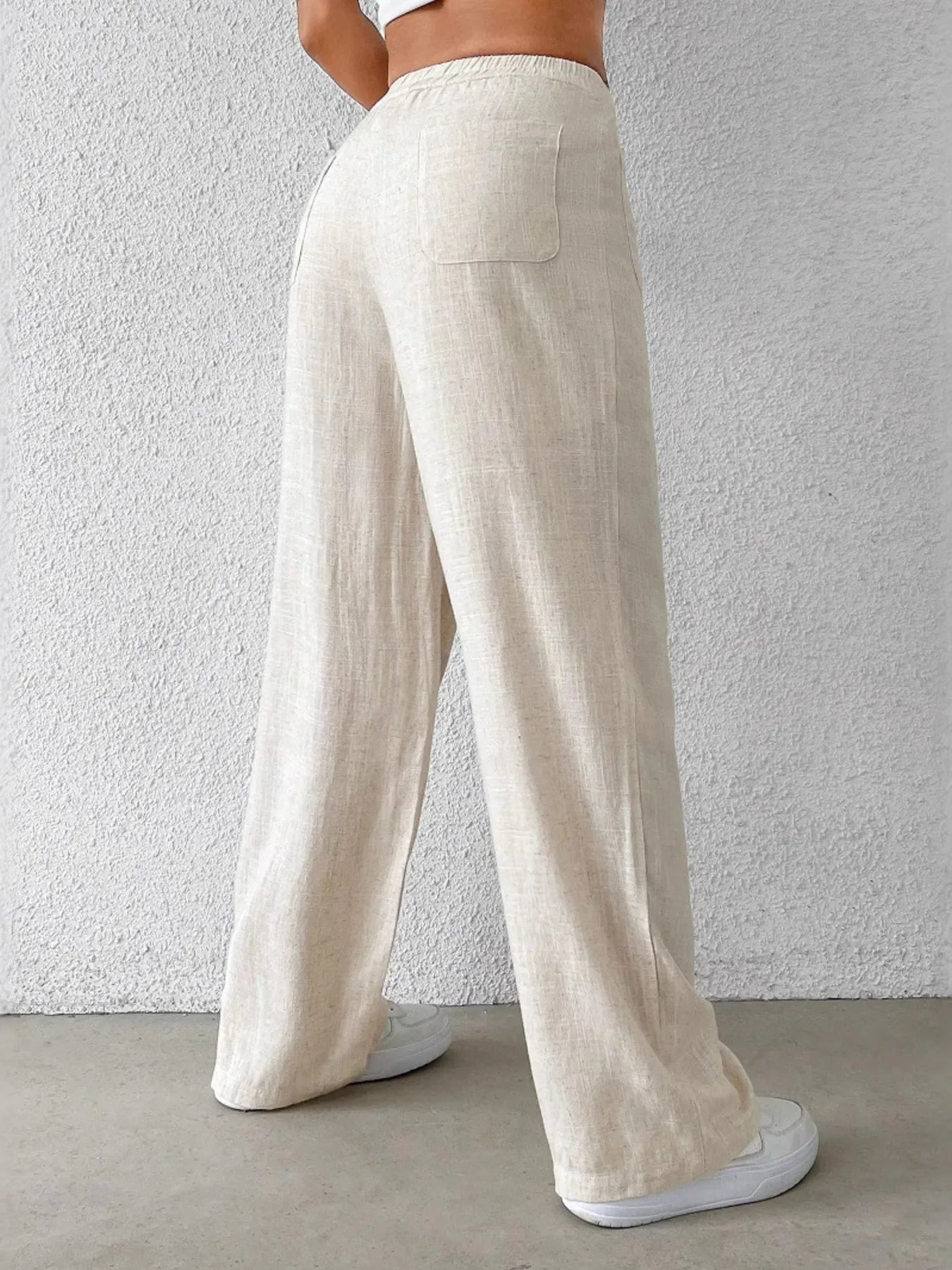 Beige wide-leg pants, back view with wide leg opening and relaxed hem.