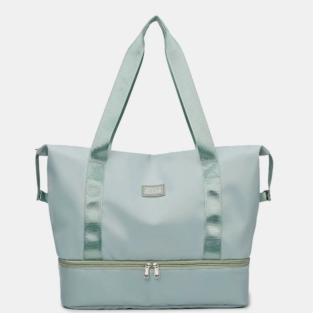 Light teal nylon tote-style duffel bag with front logo patch and zipper