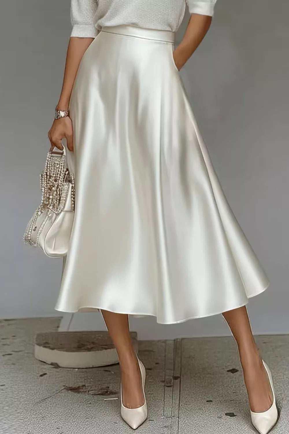 White satin A-line midi skirt with side pockets, flowing flare and knee-length hem