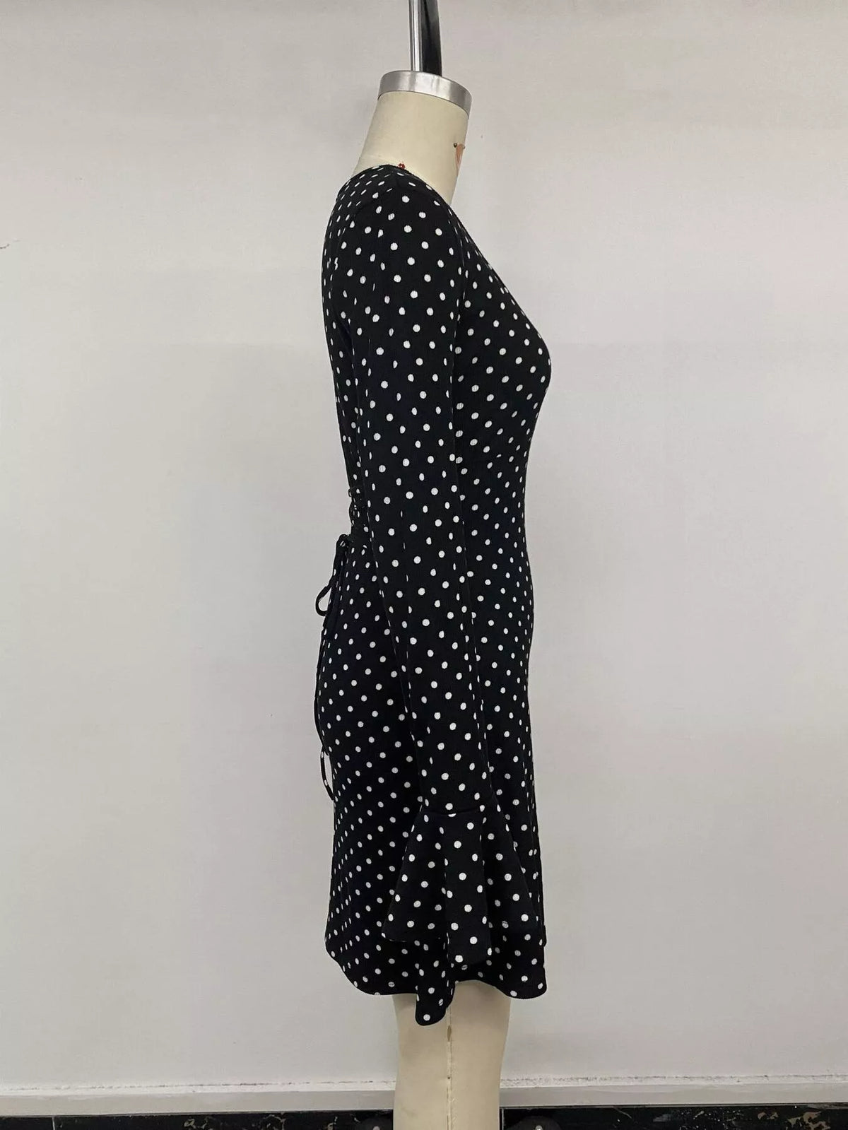 Black polka dot long sleeve mini dress, side view with gathered waist