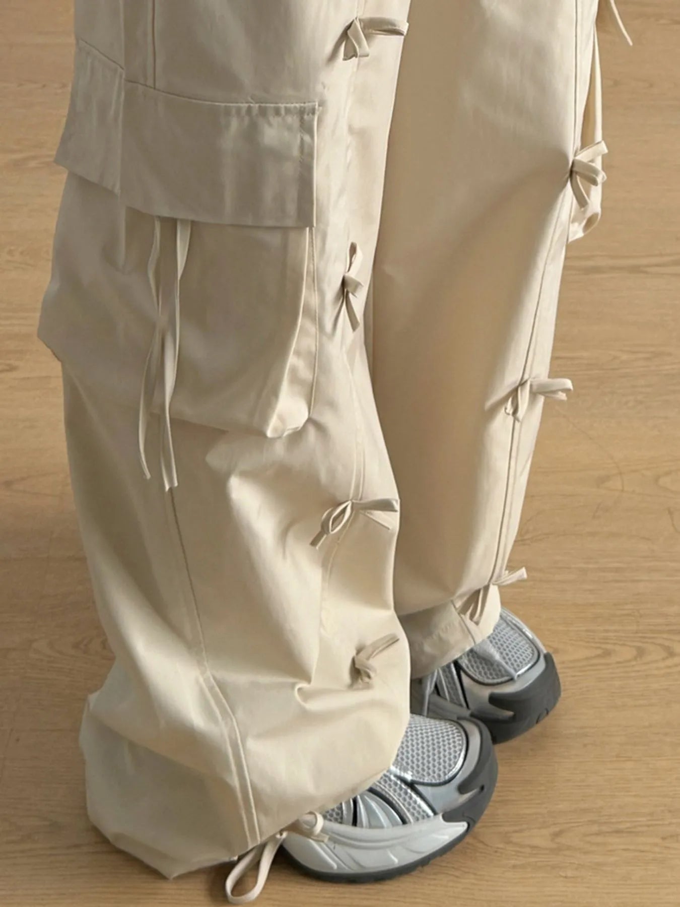 Tan cargo pants with layered cargo pockets and tie-drawcord details at the legs