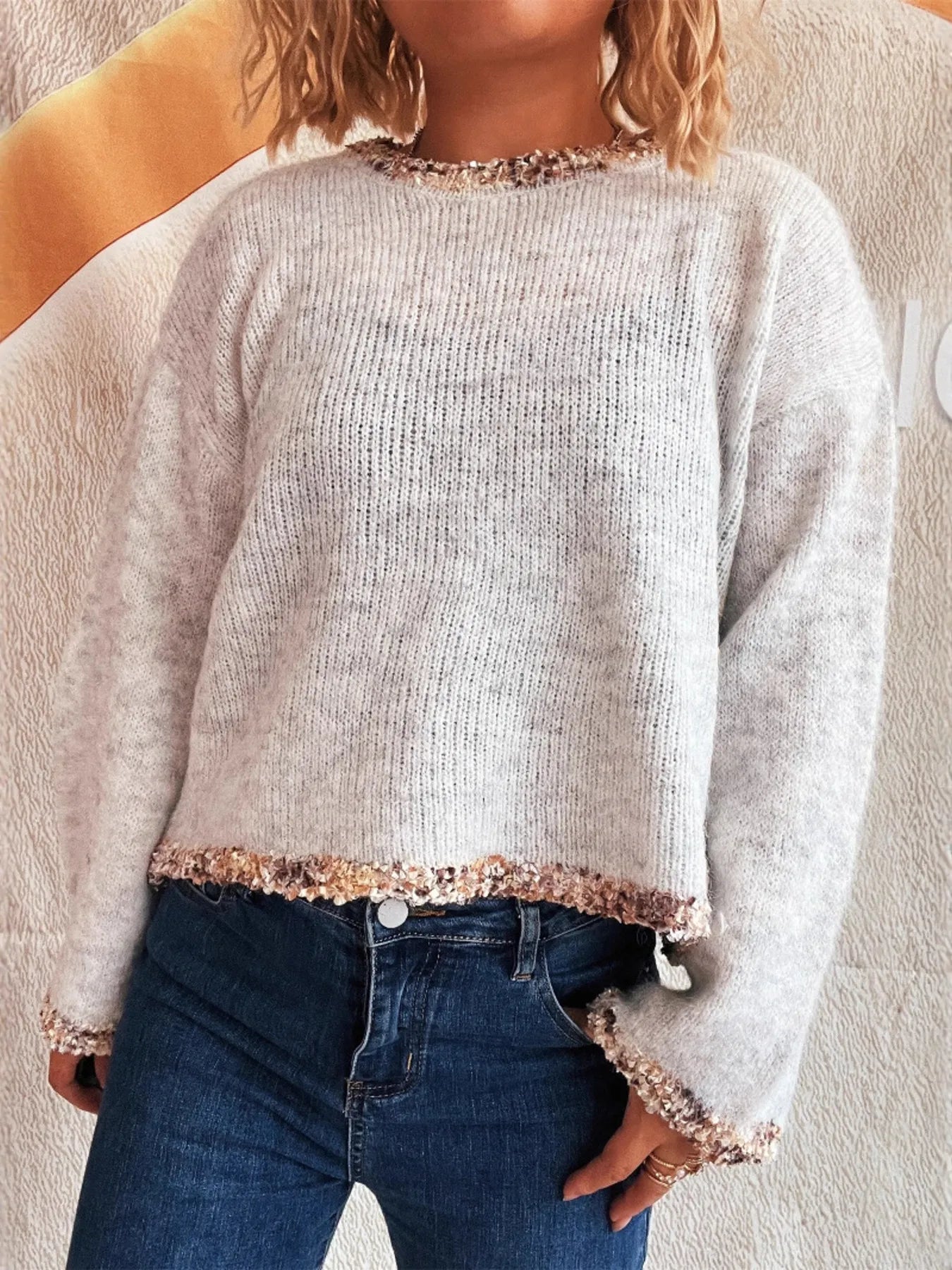 Light gray cropped knit sweater with round neckline and sparkly band trim at hem