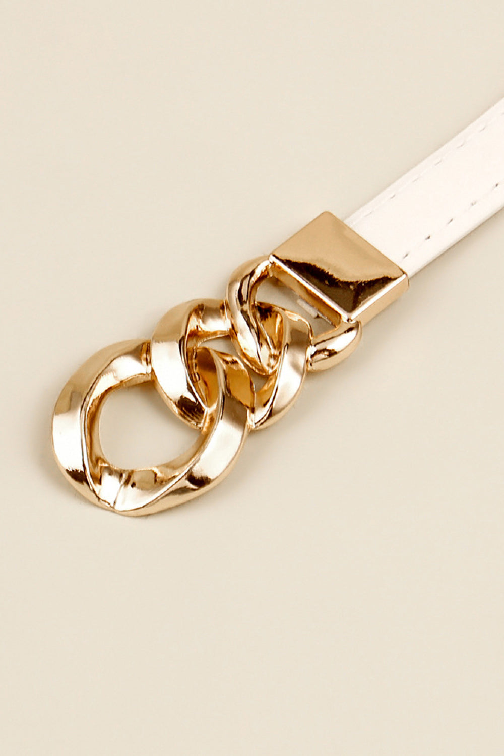 Skinny vegan leather belt buckle detail with gold chain links and rectangular plate